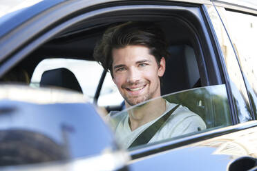 Porträt eines lächelnden Mannes am Steuer eines Autos - PNEF01987