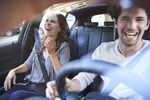 Lachendes Paar in einem Auto mit einem Mann am Steuer, lizenzfreies Stockfoto