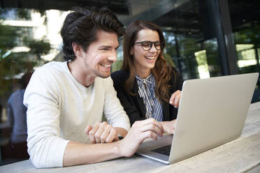 Happy businessman and businesswoman with laptop meeting in the city - PNEF01992