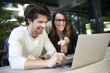 Businessman and happy businesswoman with laptop meeting in the city - PNEF01994