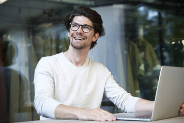 Happy businessman with laptop in the city - PNEF02008