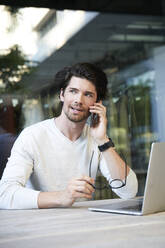 Casual businessman with laptop and cell phone in the city - PNEF02012