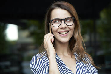 Happy businesswoman talking on the phone in the city - PNEF02026