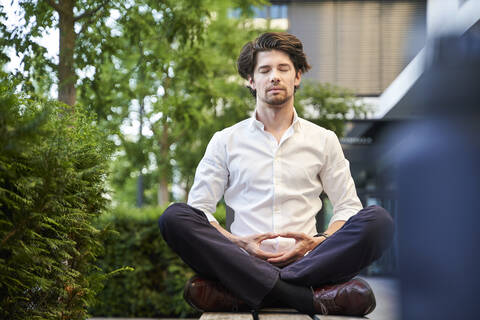 Businessman doing yoga on a bench in the city stock photo