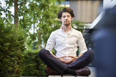 Businessman doing yoga on a bench in the city - PNEF02035
