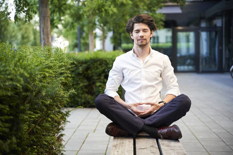 Geschäftsmann beim Yoga auf einer Bank in der Stadt, lizenzfreies Stockfoto