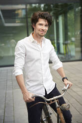 Portrait of confident man with old bicycle in the city - PNEF02048