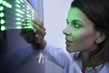 Nahaufnahme einer Frau, die einen Touchscreen mit grüner LED berührt - PNEF02075
