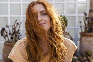 Portrait of smiling redheaded young woman on terrace - AFVF03957