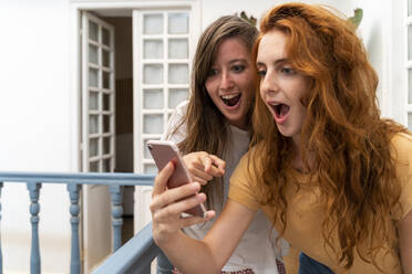 Portrait of two excited friends looking at smartphone - AFVF03961