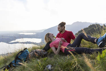 Hiking couple taking a break, lying in mountain meadow - MCVF00010