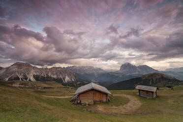 Rosa Wolken bei Sonnenuntergang auf den typischen Hütten der Geislergruppe von Seceda aus gesehen, Gröden, Trentino-Südtirol, Italien, Europa - RHPLF08991