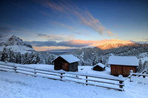Der Sonnenaufgang erhellt die verschneiten Wälder und Hütten, Passo Delle Erbe, Grödnertal, Südtirol, Italien, Europa - RHPLF09008