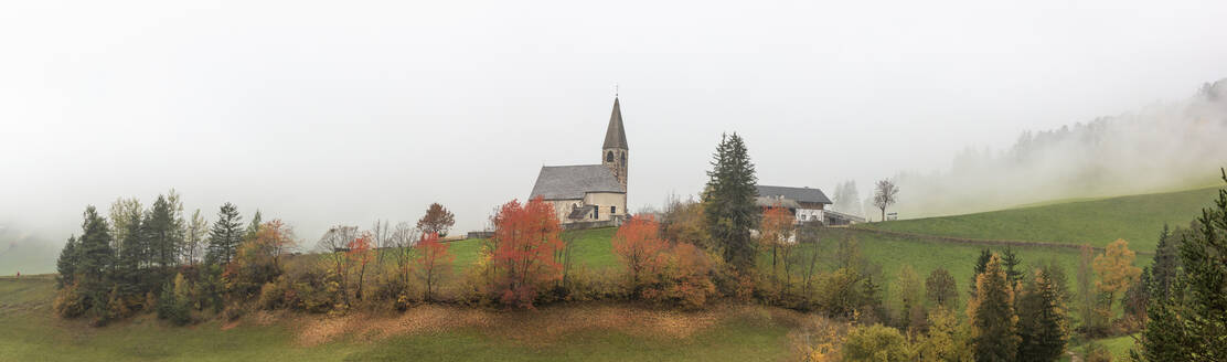 Nebel und bunte Bäume umgeben die Bergkirche im Herbst, St. Magdalena, Funes Tal, Südtirol, Dolomiten, Italien, Europa - RHPLF09016