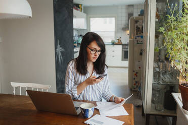 Woman using laptop and doing paper work - JOHF00232