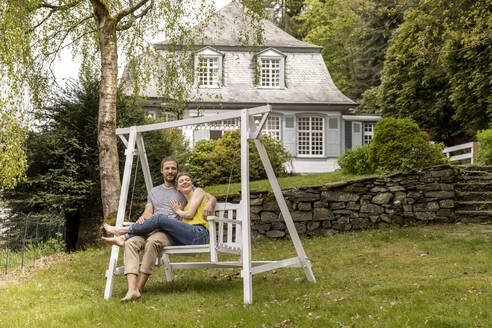 Relaxed couple in garden of their home - MJFKF00006