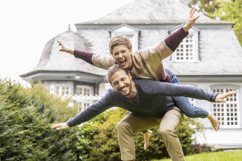 Ein glückliches Paar hat Spaß im Garten seines Hauses, lizenzfreies Stockfoto