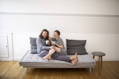 Happy young couple in pyjamas on bed couch at home stock photo