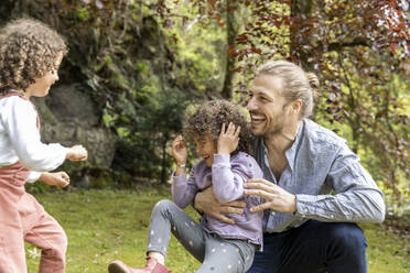 Glücklicher Vater hat Spaß mit zwei Jungen im Garten - MJFKF00028