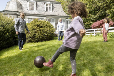 Glückliche Großfamilie beim Fußballspielen im Garten - MJFKF00036