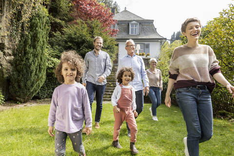 Glückliche Großfamilie bei einem Spaziergang im Garten ihres Hauses, lizenzfreies Stockfoto