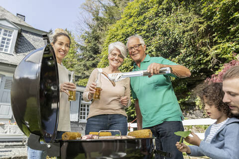 Großfamilie beim Grillen im Garten, lizenzfreies Stockfoto