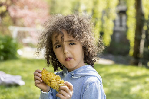Porträt eines Jungen, der einen Maiskolben im Garten isst - MJFKF00051