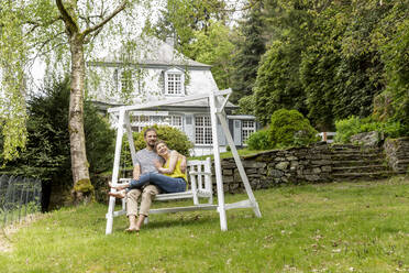 Entspanntes Paar im Garten seines Hauses - MJFKF00080