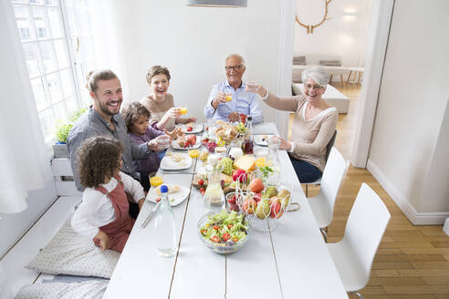 Glückliche Großfamilie beim Mittagessen zu Hause - MJFKF00111