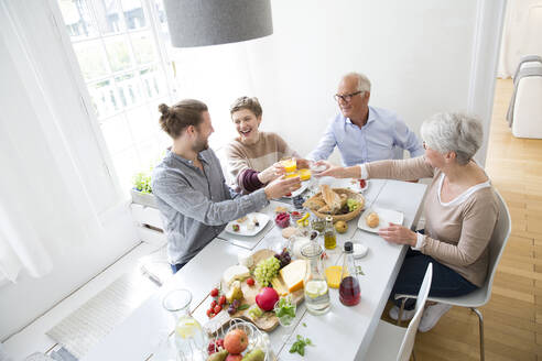 Glückliches älteres Paar mit erwachsenen Kindern beim Mittagessen zu Hause - MJFKF00120