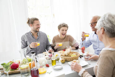 Glückliches älteres Paar mit erwachsenen Kindern beim Mittagessen zu Hause - MJFKF00121