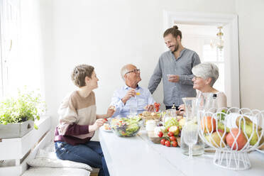 Happy senior couple with adult children having lunch at home - MJFKF00122
