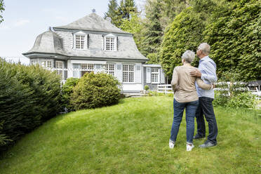 Rückansicht eines älteren Paares im Garten seines Hauses - MJFKF00124