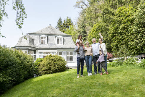 Eine glückliche Großfamilie steht im Garten ihres Hauses - MJFKF00130