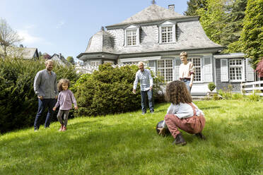 Glückliche Großfamilie beim Fußballspielen im Garten - MJFKF00133