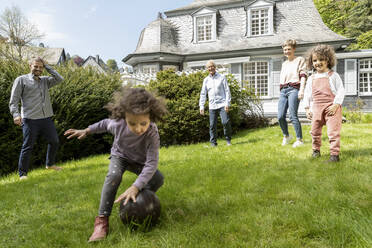 Happy extended family playing football in garden - MJFKF00134