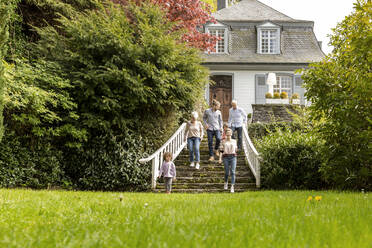 Großfamilie geht auf der Treppe im Garten ihres Hauses - MJFKF00139
