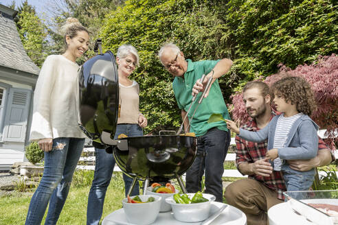 Großfamilie beim Grillen im Garten - MJFKF00143