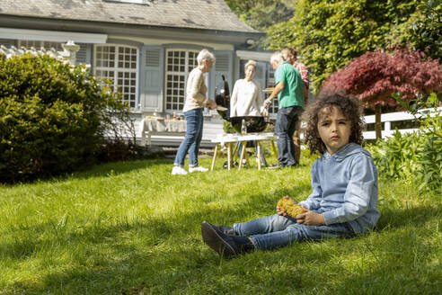 Junge mit Maiskolben bei einem Familiengrill im Garten - MJFKF00144