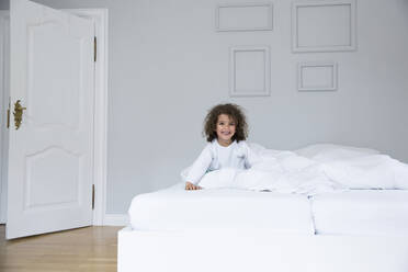 Porträt eines niedlichen glücklichen Jungen im Bett - MJFKF00152