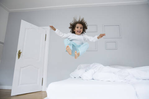 Verspielter Junge hüpft im Bett, lizenzfreies Stockfoto