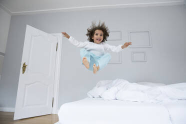 Playful boy bouncing in bed - MJFKF00153