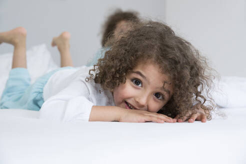 Porträt eines glücklichen Jungen mit seinem Bruder im Bett - MJFKF00157