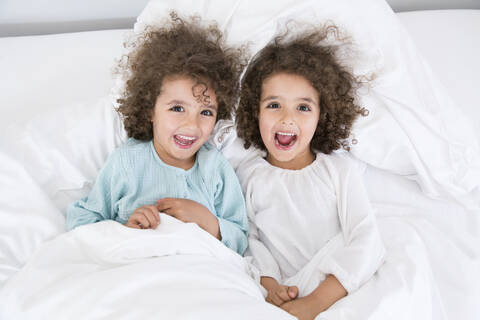 Porträt von zwei glücklichen Zwillingsbrüdern, die im Bett liegen, lizenzfreies Stockfoto