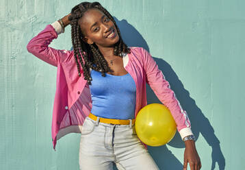 Junge schwarze Frau mit einem gelben Ball vor einer blauen Wand - VEGF00669