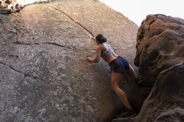 Junge asiatische Frau klettert in einer Felswand - JPTF00299