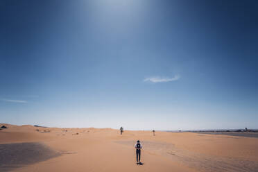 Lonely man with hat standing in the dunes of the desert of Morocco - OCMF00714