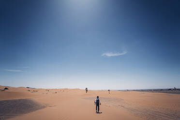 Lonely man with hat walking in the dunes of the desert of Morocco - OCMF00716