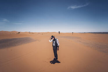 Man with a beard and hat in the dunes of the desert of Morocco - OCMF00718