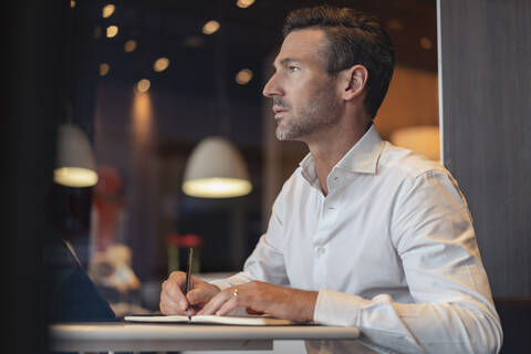 Geschäftsmann mit Tablet in einem Café macht sich Notizen, lizenzfreies Stockfoto